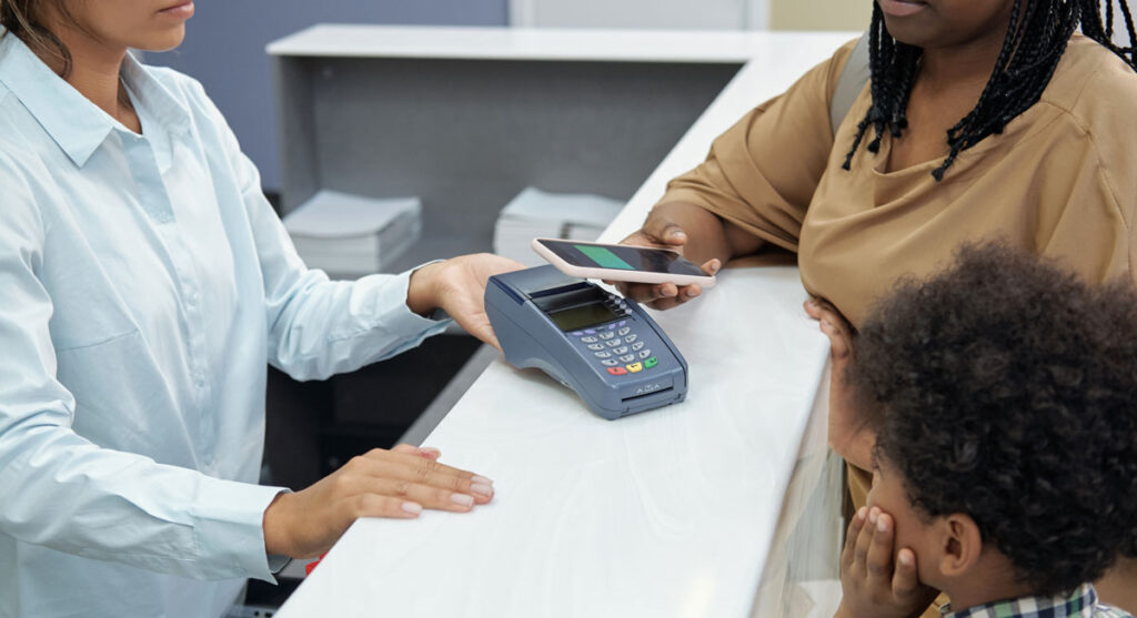 woman paying at dentists factors that affect the cost of dental implants in the uk