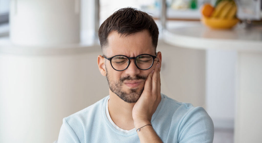 man with tooth pain risks to dental implants